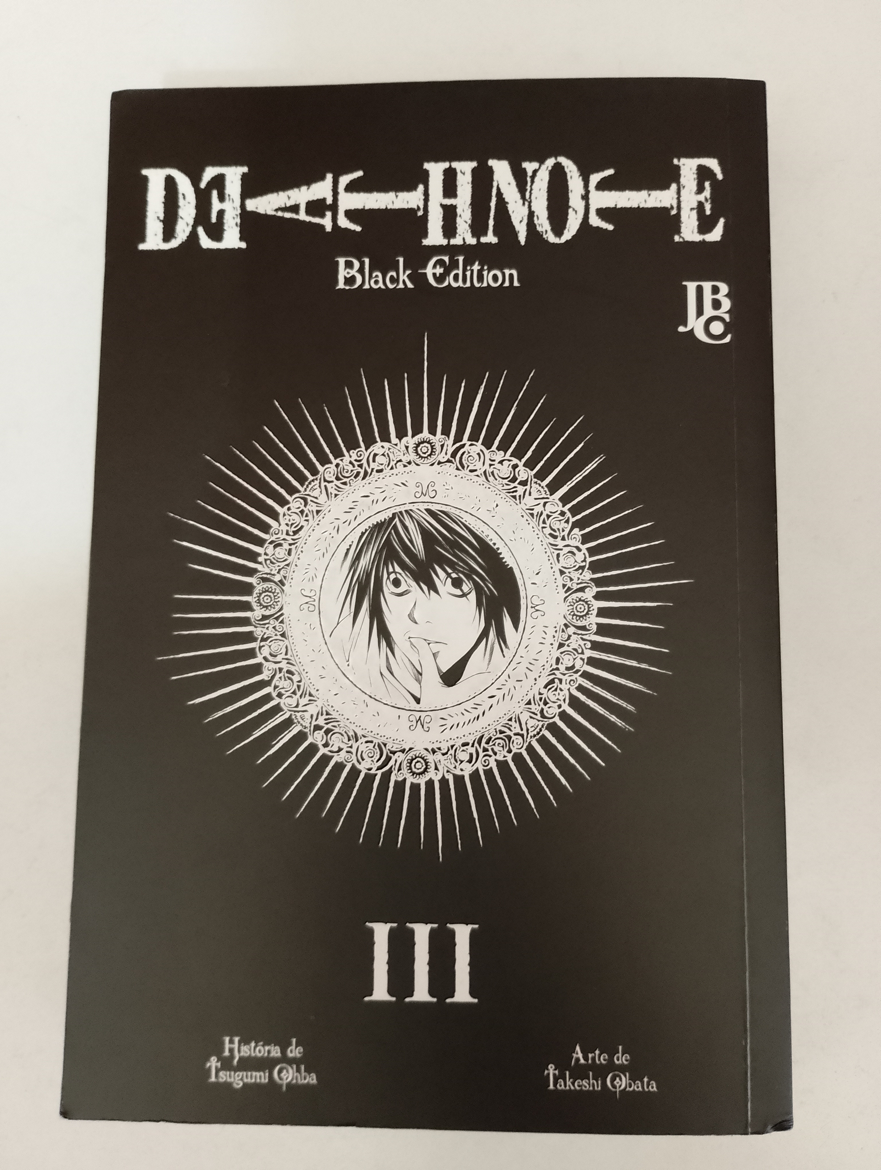 Auto-generated description: É a capa de Death Note Black Edition, volume III, com uma ilustração em preto e branco de um personagem dentro de um círculo decorativo.