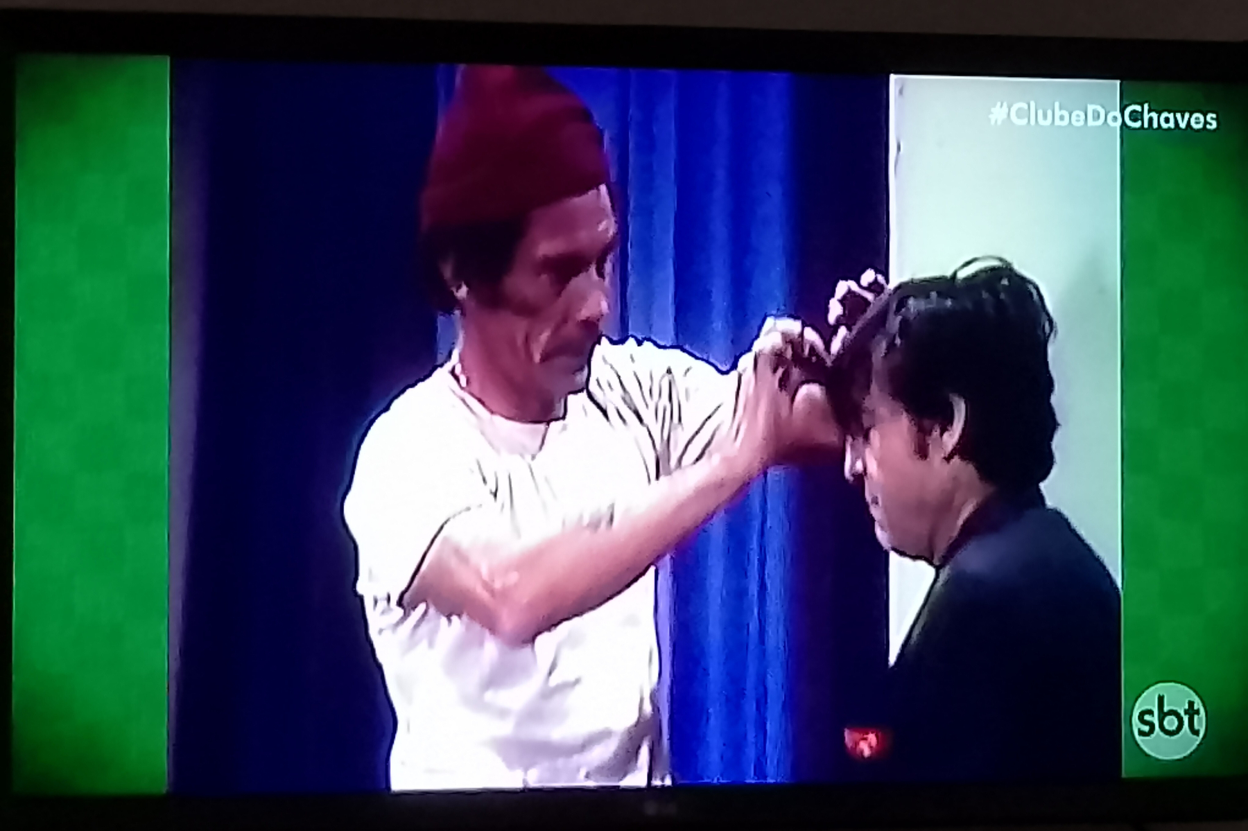 Auto-generated description: Dois personagens de uma série de TV estão interagindo, com um deles fazendo um gesto em direção à cabeça do outro.
