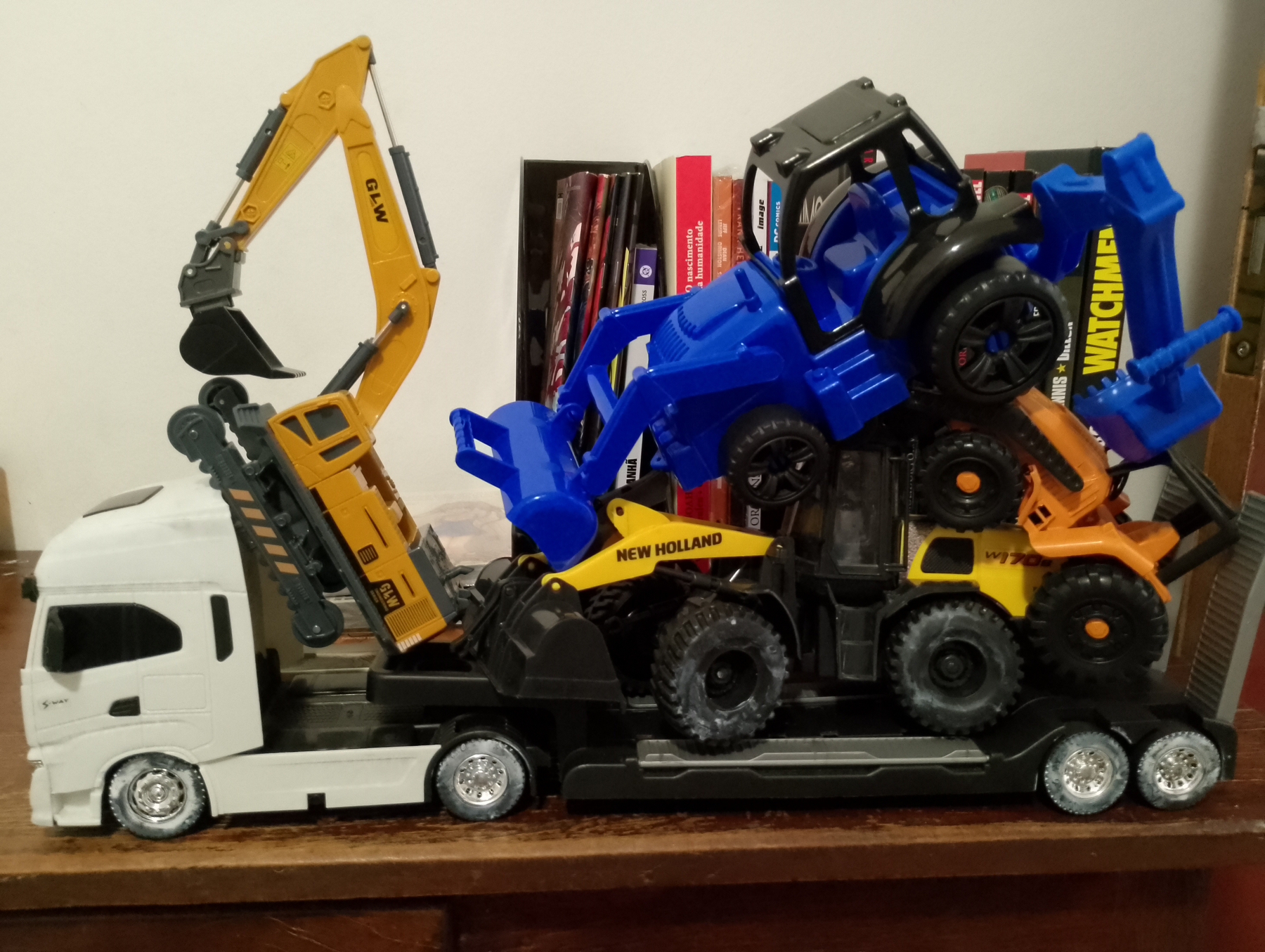 Auto-generated description: Uma pilha de brinquedos de caminhões e escavadeiras coloridos está organizada sobre um móvel.